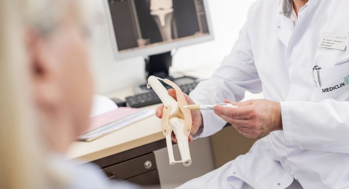 Orthopädie erklärt Funktion des Kniegelenks am Modell