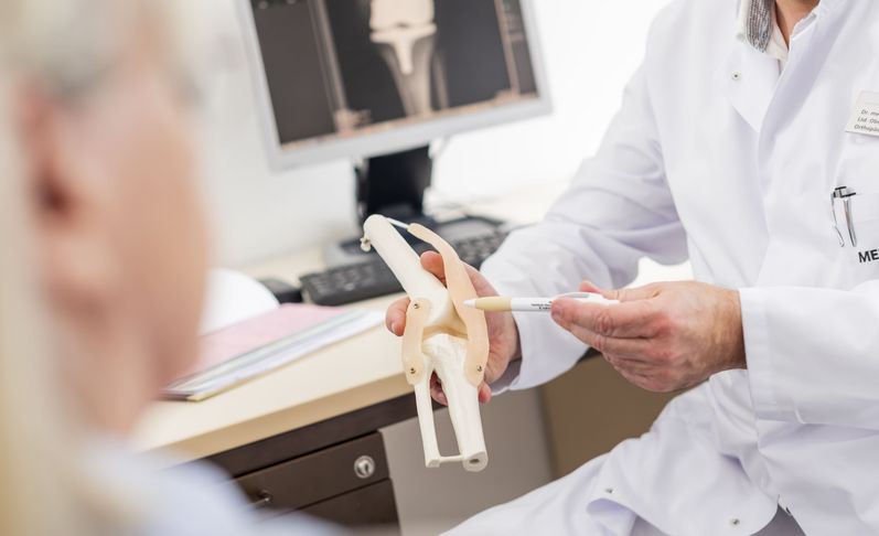 Orthopädie erklärt Funktion des Kniegelenks am Modell
