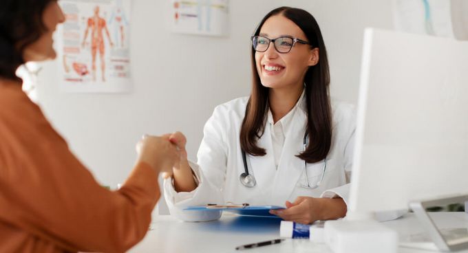 Junge Ärztin schüttelt Patientin die Hand